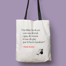 Cargar imagen en el visor de la galería, Tote bag natural con asa negra de la colección Lectorix con cita de Franz Kafka sobre la lectura en catalán