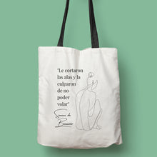 Cargar imagen en el visor de la galería, Tote bag color natural con asa negra de la colección Quotes &amp; Co con ilustración de silueta de mujer y cita de Simone de Beauvoir.