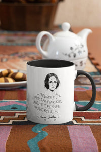 Taza blanca con asa negra con ilustración y cita de Mary Shelley en inglés.