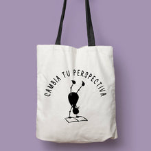 Cargar imagen en el visor de la galería, Tote bag natural con asa negra con la ilustración del personaje Lectorix y el texto &quot;Cambia tu perspectiva&quot;
