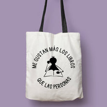 Cargar imagen en el visor de la galería, Tote bag natural con asa negra con la ilustración del personaje Lectorix y el texto &quot;Me gustan más los libros que personas&quot;